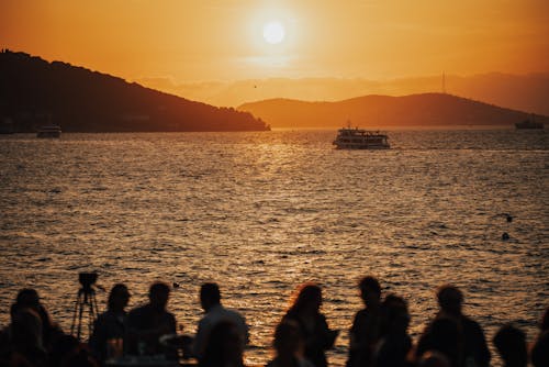 Silhouettes of People on Seashore on Sunset