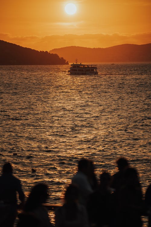 Silhouettes of People near Water on Sunset