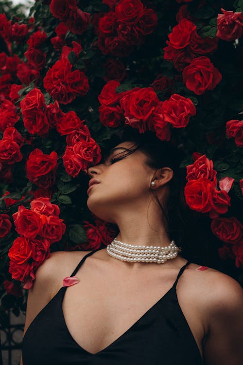Woman Posing against a Red Rosebush 