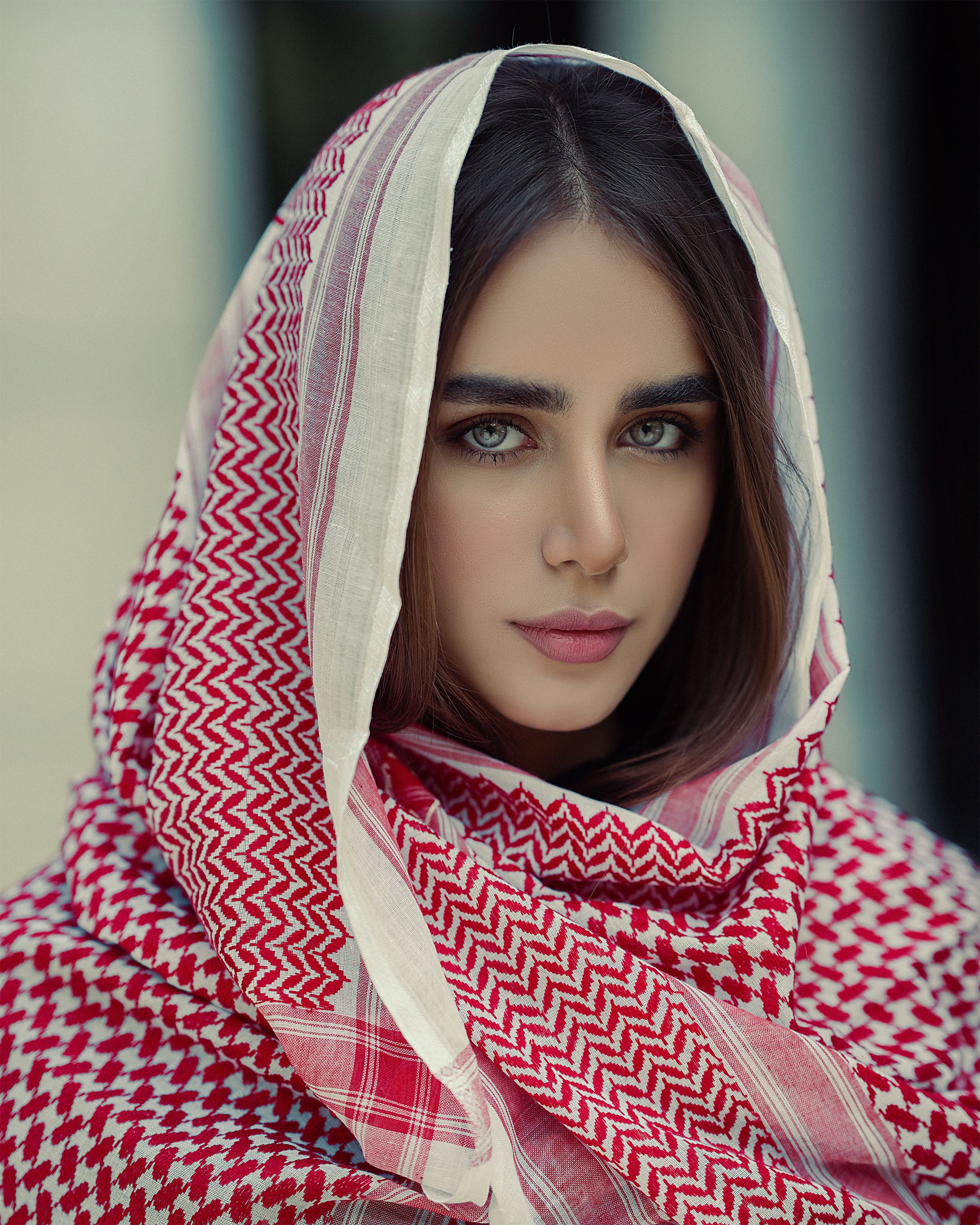 Stunning portrait of a woman wrapped in a red and white keffiyeh, capturing elegance and grace.