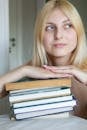 A young woman is holding a stack of books