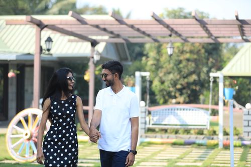 Free A smiling couple holding hands and walking outdoors on a sunny day. Stock Photo