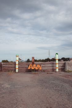 Rustic warning sign and barricade in Toyohashi, Japan, under a moody sky.