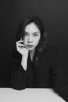 Black and white portrait of a young woman in a studio setting, exuding elegance.