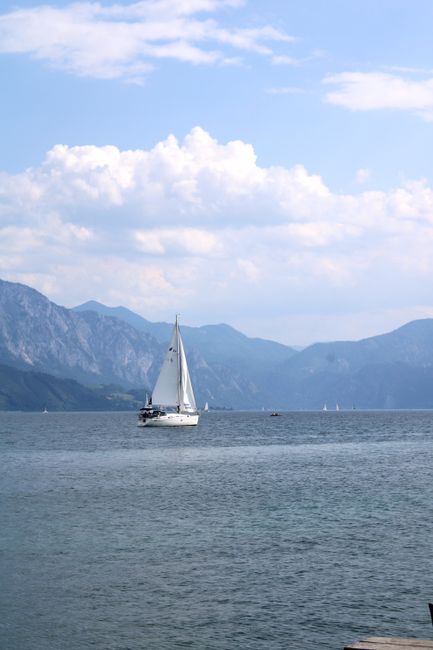 Peaceful scene of a sailboat on Attersee Lake against a mountain backdrop.
