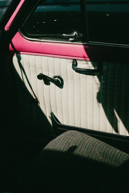 Aesthetic vintage car interior featuring pink trim and textured seat with dramatic shadows.