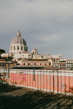 The majestic dome of St. Peter's Basilica seen from a rooftop in Rome, Italy, capturing the city's historical charm.