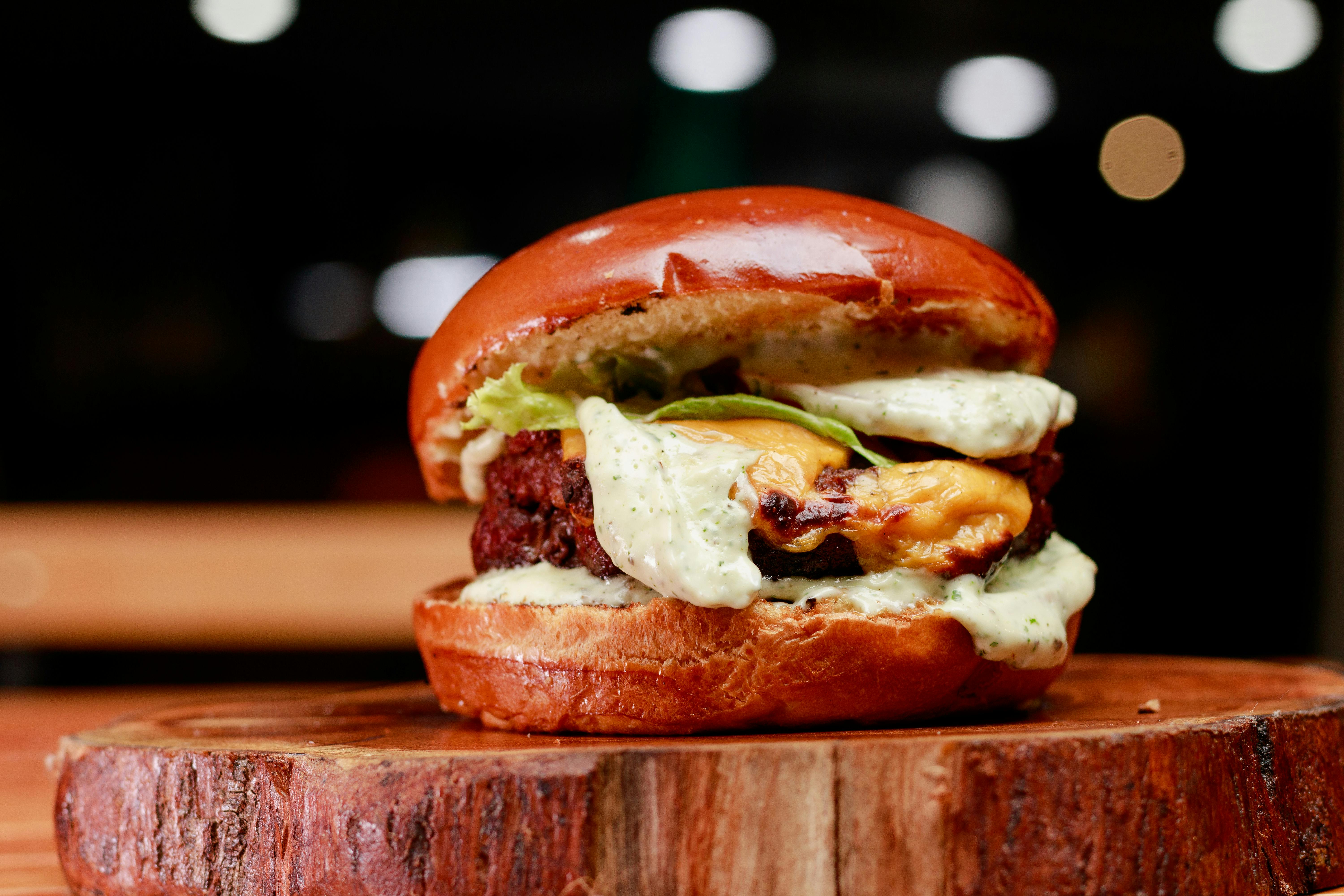 Close-up of a gourmet burger with cheese on a wooden board in Recife, Brazil.
