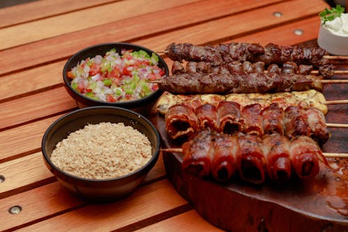 Meat Skewers and a Salad Bowl on a Wooden Table