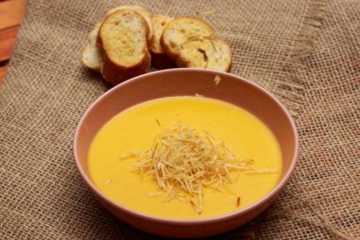 Delicious creamy pumpkin soup served with crispy bread slices in a rustic setting.