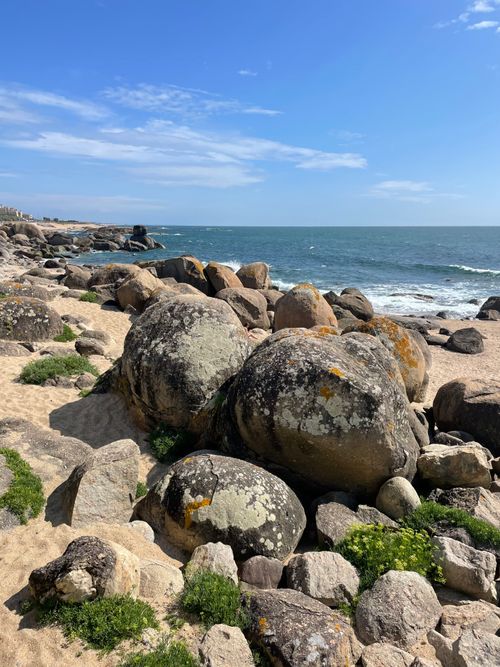 Free Peaceful beach scene with large rocks and waves under a blue sky, perfect for summer vibes. Stock Photo