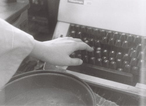 Person Tapping on Typewriter