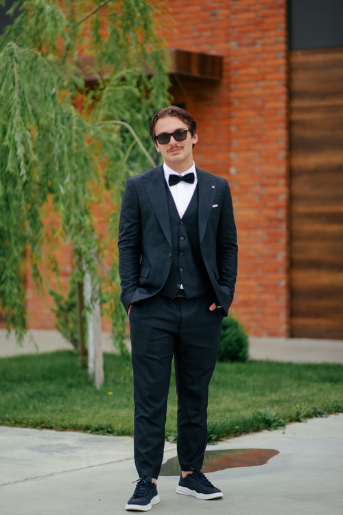 Free Man in a black suit and sunglasses posing confidently outdoors. Stock Photo