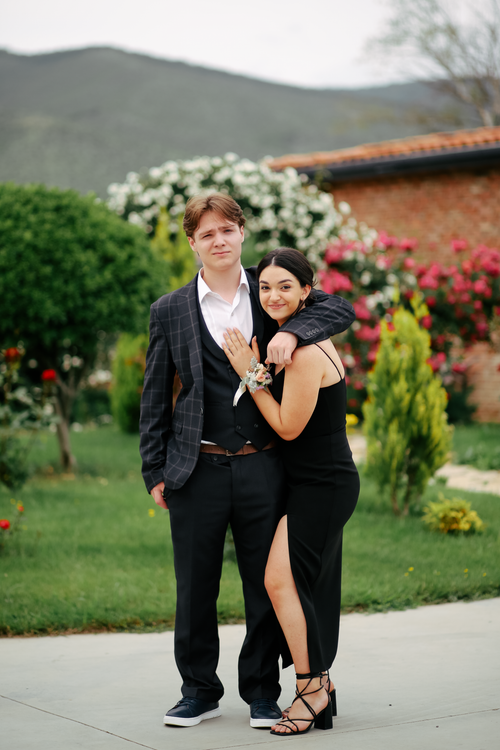 Free A stylish couple in elegant attire embracing outdoors in a scenic garden setting. Stock Photo