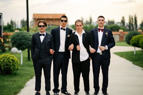 Free Group of well-dressed groomsmen posing outdoors in formal suits. Stock Photo