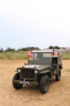 World War II vintage Jeep with flags on Normandy beach, France.