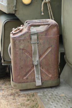 Rusty vintage military fuel can attached to an old vehicle outdoors.