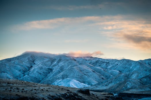 Snow-covered mountains under a colorful sunset sky, creating a serene outdoor scene.