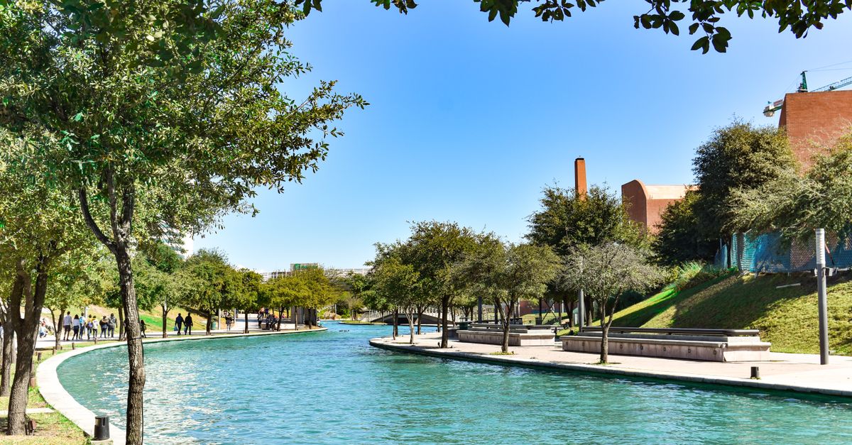 Peaceful riverwalk in Monterrey, Mexico, featuring lush trees and tranquil water.