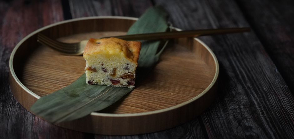 A golden vanilla butter cake on a wire rack with one slice cut, showing a fine, tender crumb.