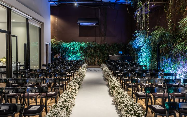 Beautifully decorated indoor wedding ceremony venue with a floral aisle and elegant chairs.