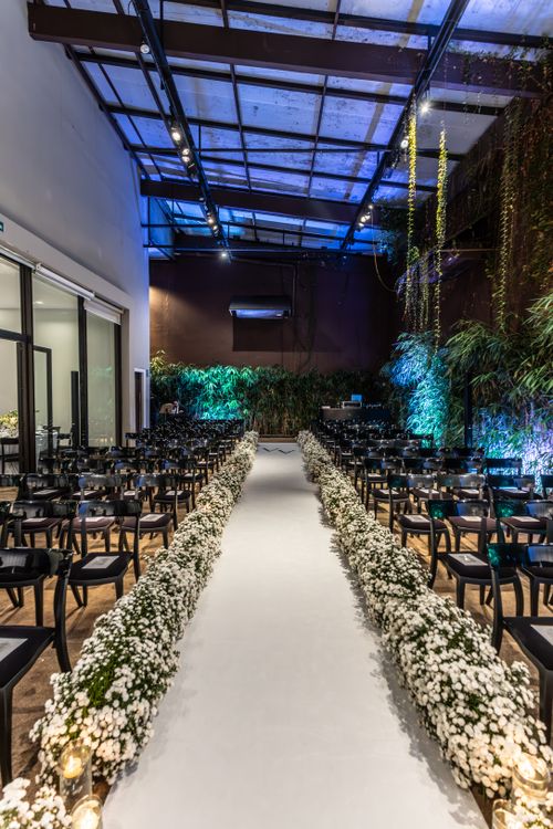 Free Beautifully decorated indoor wedding ceremony venue with a floral aisle and elegant chairs. Stock Photo