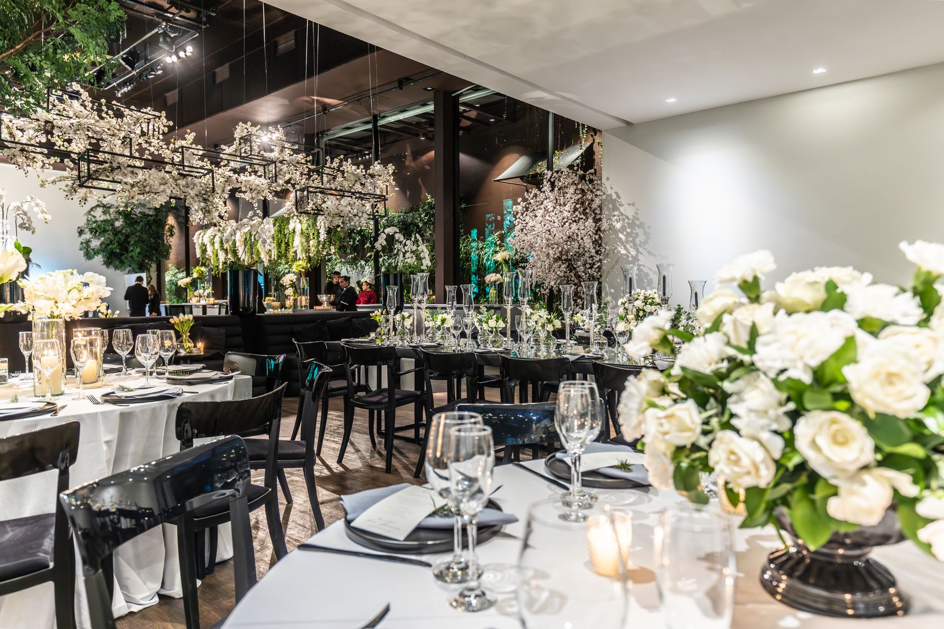 Beautifully arranged wedding venue with flowers, table settings, and wineglasses.