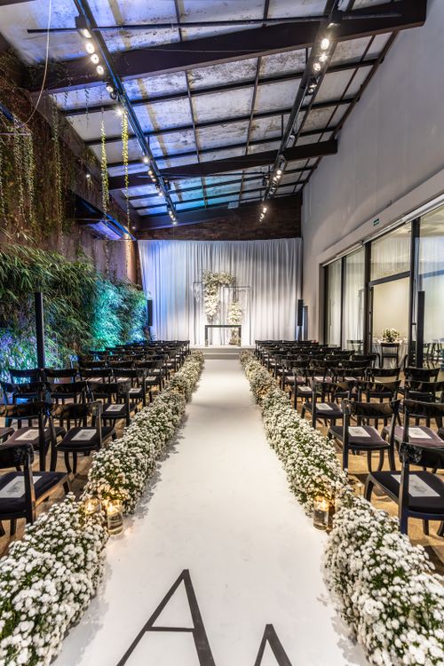Free Beautifully decorated indoor wedding aisle with floral arrangements and seating Stock Photo