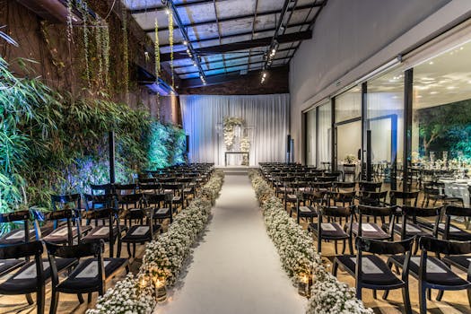 Beautifully decorated wedding venue with aisle, chairs and floral arrangements indoors.