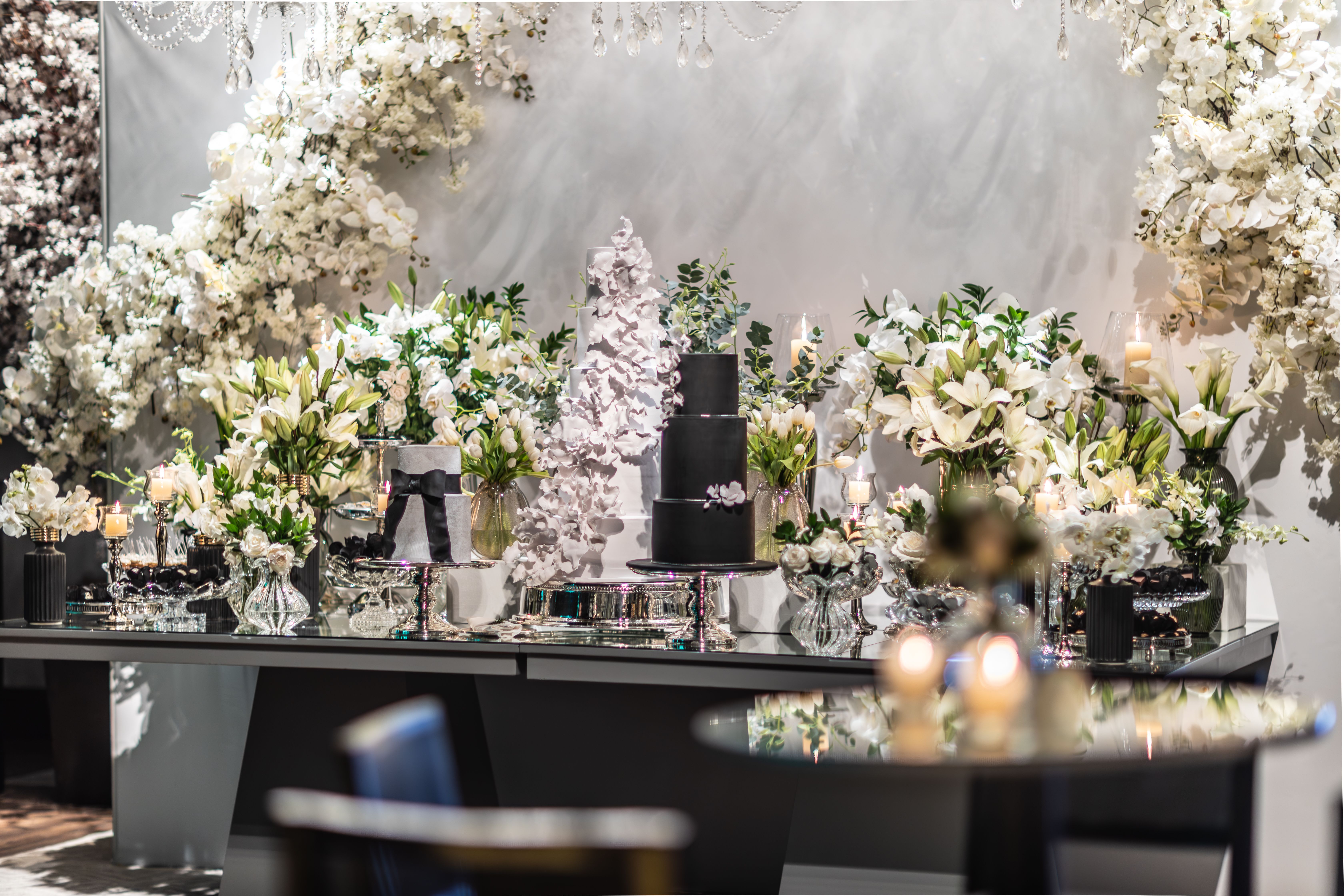 Warm Charcoal + Ivory + Black, minimalist wedding decor with white floral arrangements and a black wedding cake illustrating the charcoal wedding palette