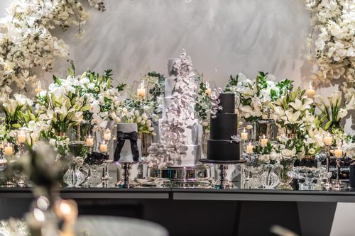 Free Luxurious wedding reception setup featuring white floral decor, candles, and elegant cakes. Stock Photo