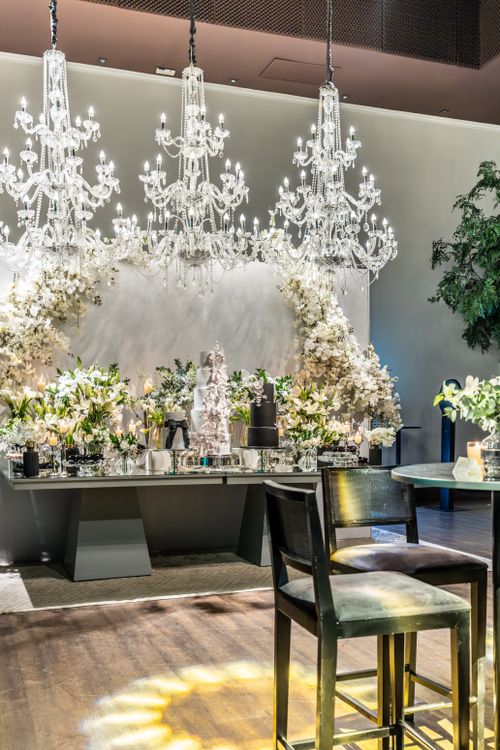 Free Elegant wedding reception setup featuring chandeliers, white flower arrangements, and a luxurious ambiance. Stock Photo