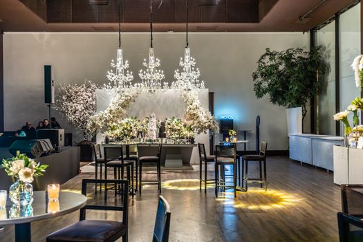 Beautifully decorated event venue featuring chandeliers and floral arrangements, perfect for weddings or banquets.