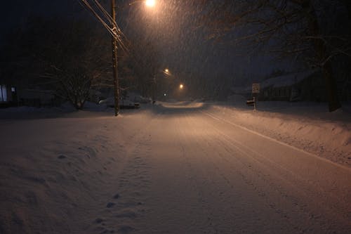 Snowfall over Road in Village at Night