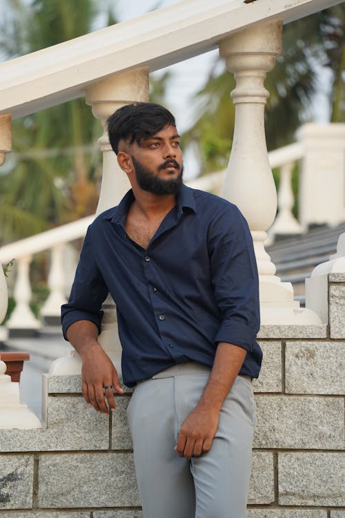 Model in a Navy Blue Shirt and Gray Pants Leaning on the Stairs