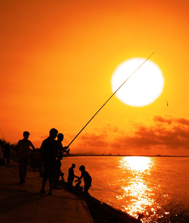 Free Sun on Yellow Sky over People on Sea Shore Stock Photo