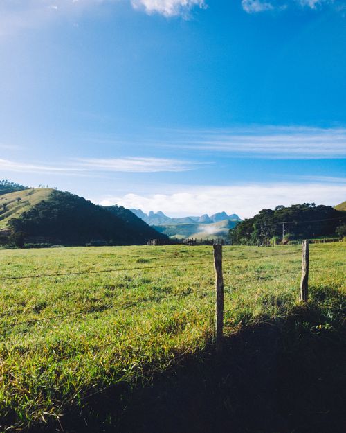 Free Beautiful countryside landscape with a barbed wire fence under a clear blue sky. Stock Photo