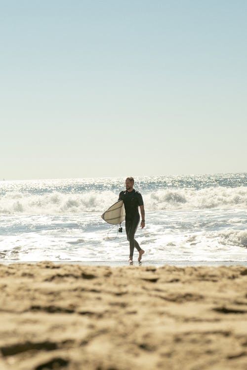 Surfer Walking with Surfboard on Sea Shore