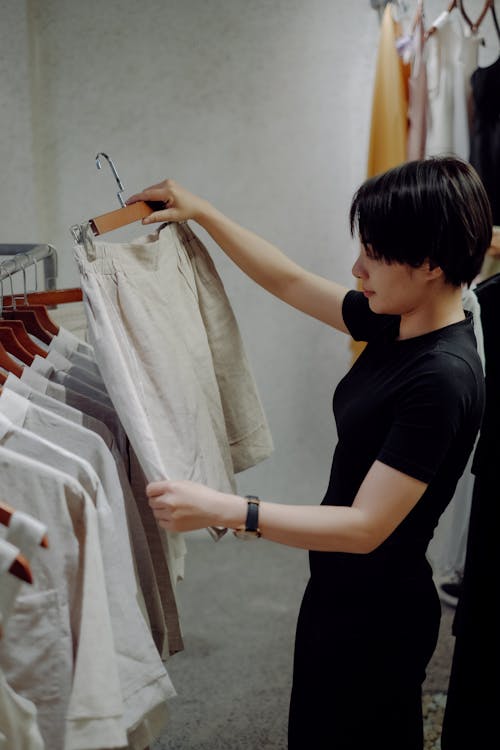 Young Woman Holding a Hanger with Shorts at a Clothing Store 