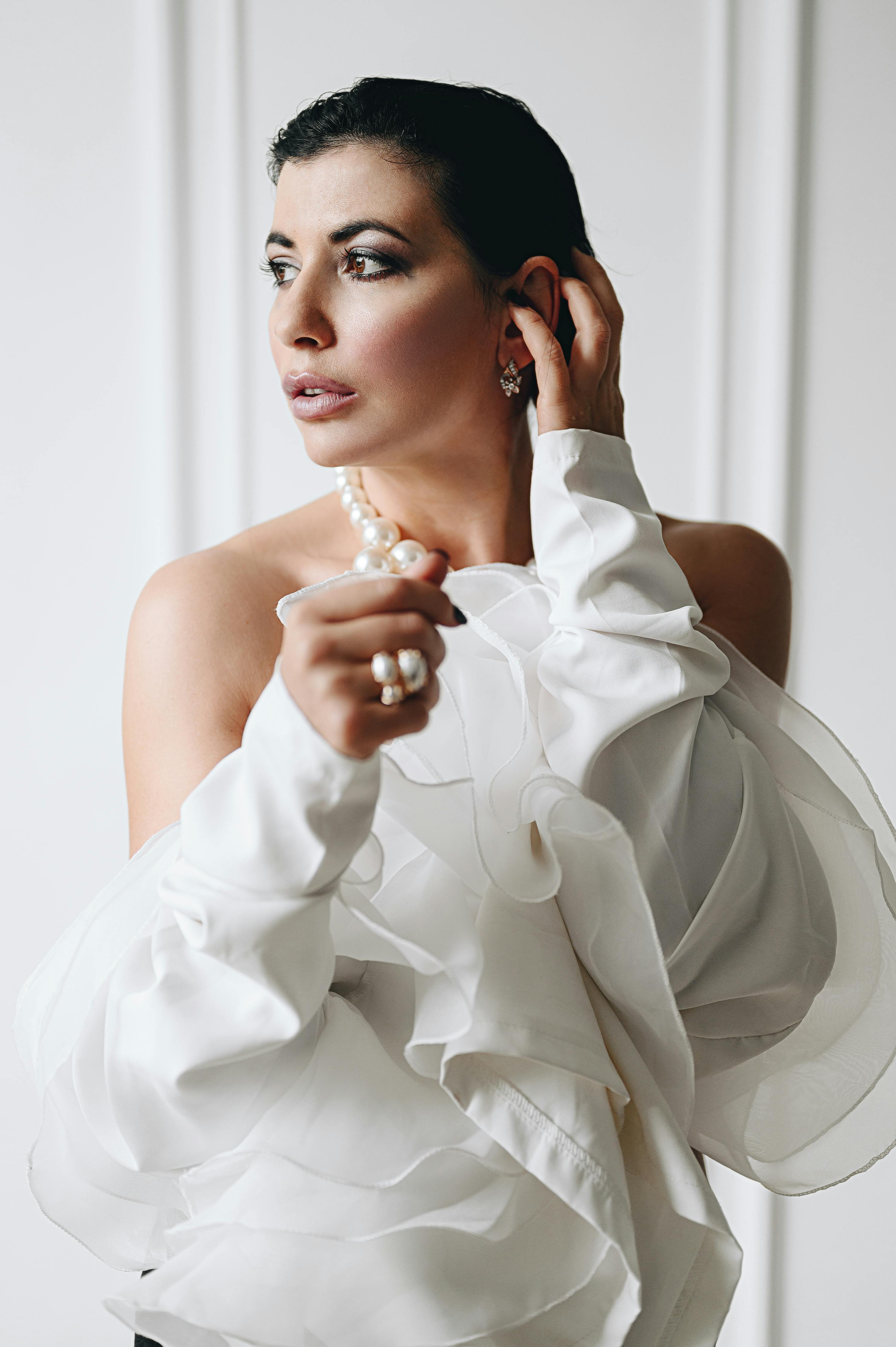 Sophisticated portrait of woman in white ruffles, gazing thoughtfully.