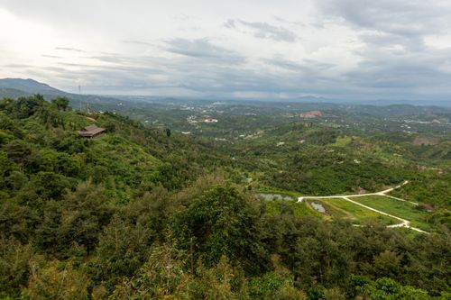 Free Breathtaking aerial view of lush green hills and countryside landscape under a dramatic cloudy sky. Stock Photo