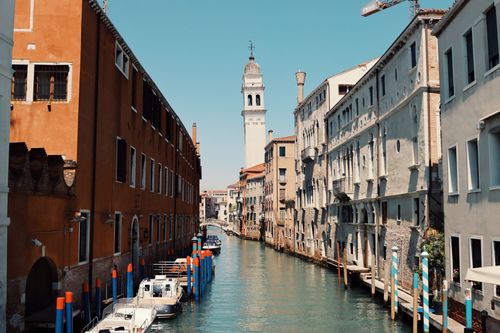 Free Beautiful view of a canal in Venice, Italy, featuring a historic tower and colorful buildings. Stock Photo