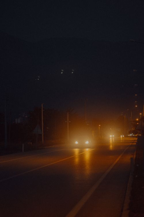 Free Moody night shot capturing car headlights on the quiet streets of Muğla, Türkiye. Stock Photo