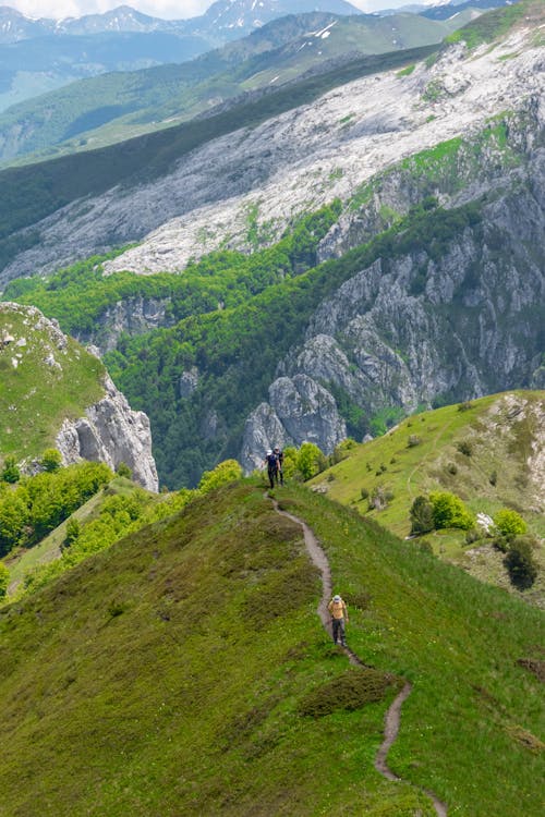 People Walking on a Path in a Mountain Valley 
