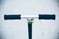 特写镜头中，一辆黑色滑板车停在街道背景模糊的画面里