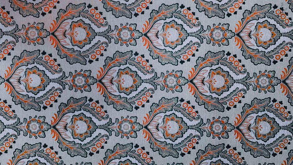 Detailed ornate floral pattern on fabric, showcasing intricate design and vibrant colors.