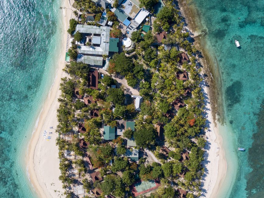 A breathtaking aerial shot capturing a tropical island resort surrounded by azure waters and sandy beaches.
