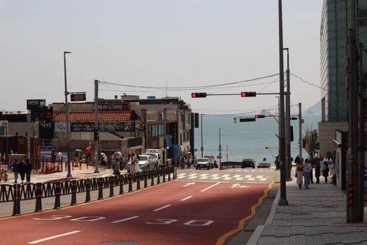 Vibrant coastal road scene in South Korea with people and ocean view.