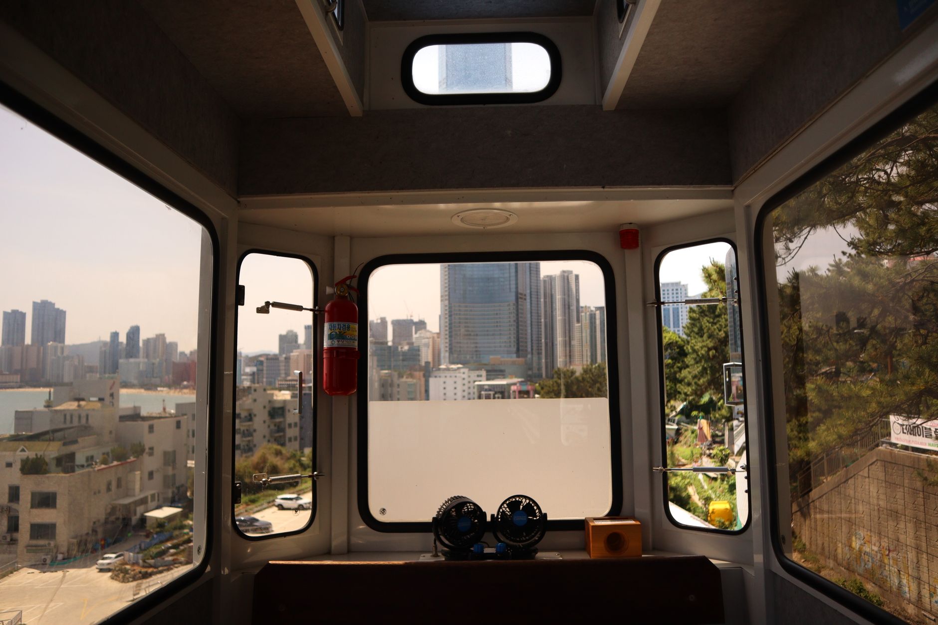 Panoramic view of a city skyline from inside a train cabin during daytime.
