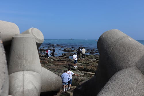 Tourist Playing by the Coast near Concrete Tetrapod